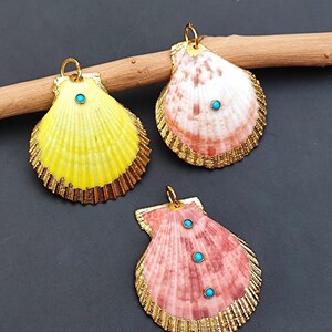 K&ouml;nnte beinhalten: Drei goldger&auml;nderte Muscheln mit t&uuml;rkisfarbenen Akzenten. Die Muscheln sind gelb, rosa und wei&szlig; mit einer nat&uuml;rlichen, strukturierten Oberfl&auml;che.