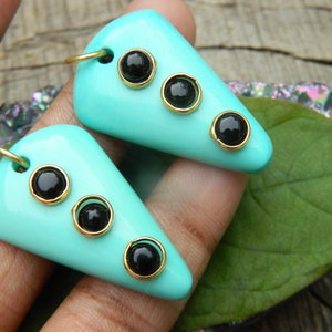 Puede incluir: Un par de pendientes de color azul turquesa con tres piedras de ónix negro engastadas en oro.