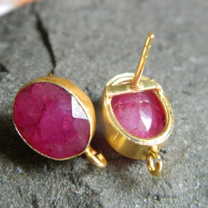 Puede incluir: Un par de pendientes de oro con piedras preciosas de rubí rosa. Los pendientes tienen un cierre de poste y un pequeño bucle en el lateral.