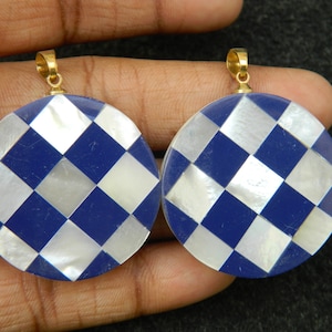 May include: Two round pendants with a checkerboard pattern of blue lapis lazuli and white mother of pearl. Each pendant has a gold bail.
