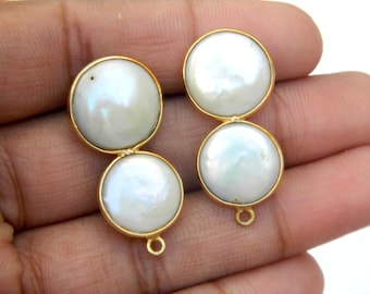 Peut inclure: Deux paires de boucles d'oreilles dorées, chacune avec deux grandes perles blanches rondes. Les perles ont un léger éclat irisé. Les boucles d'oreilles ont un design simple et élégant avec une petite boucle en bas pour l'attache.