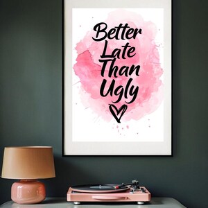 Puede incluir: Una impresión enmarcada con un fondo de acuarela rosa y el texto "Better Late Than Ugly" en letras negras con un pequeño corazón en la parte inferior.