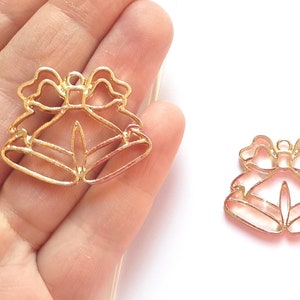 May include: Three gold metal Christmas bell charms with a bow design. The charms are perfect for adding a festive touch to crafts and jewelry.