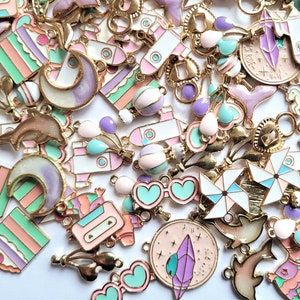 May include: Assortment of colorful enamel charms with gold-tone metal findings. The charms feature various designs including a rocket, a crescent moon, a dolphin, a cake, a unicorn, a pinata, a wind spinner, and sunglasses.