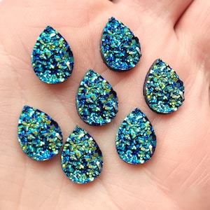 Puede incluir: Surtido de ocho cabujones de resina en forma de lágrima de color azul verdoso y verde iridiscente. Los cabujones tienen un acabado brillante y brillante.