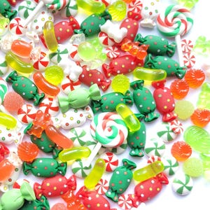 May include: A colorful assortment of candies, including red and green wrapped candies, lollipops, and gummy bears. The candies are in various shapes and sizes, with red, white, green, and orange colors. Some candies have polka dots.