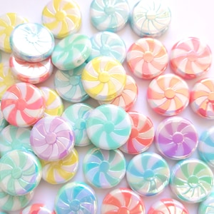 May include: Assortment of colorful candy-shaped buttons with a swirl design. The buttons are made of plastic and have a glossy finish.