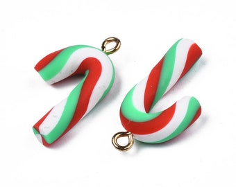 May include: Two red, white, and green candy cane charms with gold jump rings. The candy canes are made of polymer clay and are perfect for adding a festive touch to jewelry or crafts.