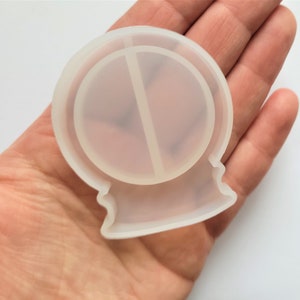 May include: Clear silicone mould shaped like a snow globe with a round, flat base and a raised, rounded top. The mould has a seam down the centre.