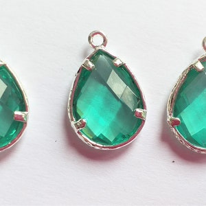 May include: Three teardrop-shaped pendants with a silver-toned metal frame and a bright green glass centre.