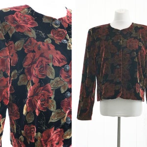 May include: A black velvet jacket with a red and gold floral pattern. The jacket has a button closure and long sleeves.