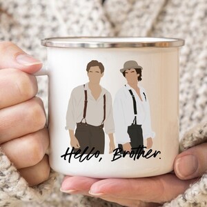 May include: White enamel mug featuring a black and white illustration of two men in hats and braces. The text "Hello, Brother." is printed beneath the illustration.