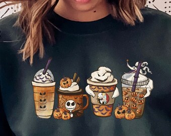May include: A dark green sweatshirt with a graphic of four Halloween-themed coffee cups. The cups are decorated with pumpkins, ghosts, and a Jack Skellington character.