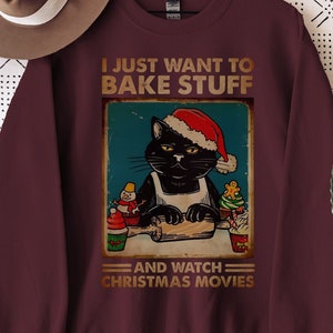 Könnte beinhalten: Ein maroonfarbener Pullover mit einer Grafik im Vintage-Stil eines schwarzen Katers, der einen Weihnachtsmann-Hut trägt und backt. Der Text lautet "Ich möchte nur backen und Weihnachtsfilme schauen".