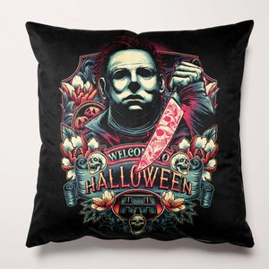 Könnte beinhalten: Schwarzes quadratisches Kissen mit einer Grafik eines Mannes, der ein blutiges Messer hält, und dem Text "WELCOME TO HALLOWEEN". Das Design umfasst Totenköpfe, Blumen und ein Haus. Dekorativer Artikel.
