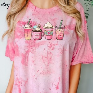 Puede incluir: Camiseta rosa tie-dye con un gr&aacute;fico de cuatro tazas de caf&eacute; diferentes. Las tazas tienen diferentes dise&ntilde;os y una de ellas dice "Mom Fuel".