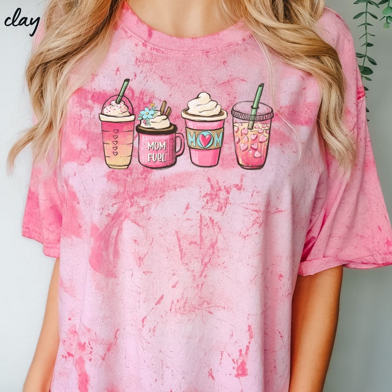 Puede incluir: Camiseta rosa tie-dye con un gr&aacute;fico de cuatro tazas de caf&eacute; diferentes. Las tazas tienen diferentes dise&ntilde;os y una de ellas dice "Mom Fuel".