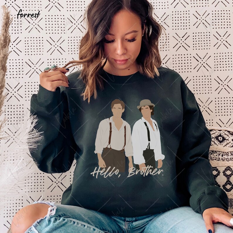 May include: A dark green sweatshirt featuring a graphic print of two men in white shirts and braces. The text "Hello, Brother." is printed below the graphic.