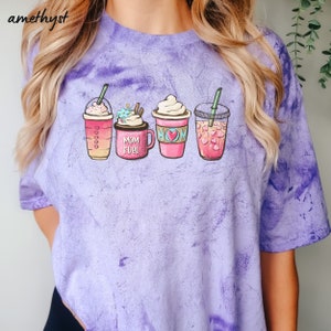 Puede incluir: Camiseta de color morado tie-dye con un gr&aacute;fico de cuatro bebidas de caf&eacute; diferentes. Las bebidas est&aacute;n etiquetadas como "Mom Fuel" y "Mom".