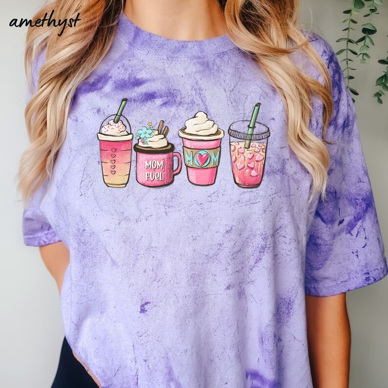 Puede incluir: Camiseta de color morado tie-dye con un gr&aacute;fico de cuatro bebidas de caf&eacute; diferentes. Las bebidas est&aacute;n etiquetadas como "Mom Fuel" y "Mom".