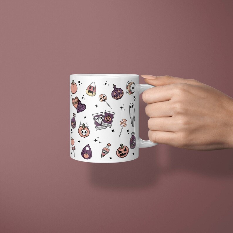 May include: White ceramic mug with a Halloween-themed design. The mug features a variety of spooky and cute illustrations, including pumpkins, ghosts, candy corn, and potion bottles. The design is in shades of purple, orange, and black.