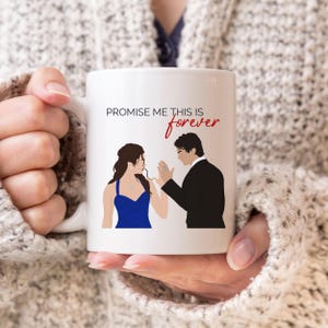 May include: White ceramic coffee mug with a black and blue illustration of a couple. The text "Promise me this is forever" is printed in red on the mug.