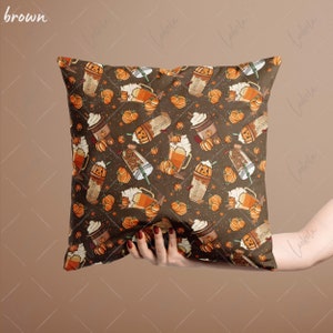 May include: A brown throw pillow with a fall-themed pattern featuring pumpkins, coffee cups, and cinnamon sticks. The pattern is repeated throughout the pillow.