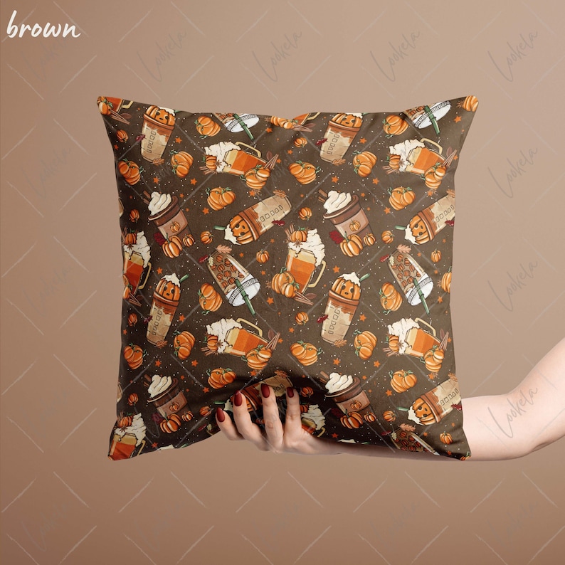 May include: A brown throw pillow with a fall-themed pattern featuring pumpkins, coffee cups, and cinnamon sticks. The pattern is repeated throughout the pillow.
