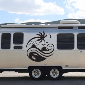 May include: A silver camper van with a black decal of a palm tree, sun, moon, and waves on the side. The decal also includes a beach chair and umbrella.