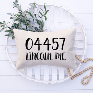 May include: A white pillow with black text that reads "04457 LINCOLN, ME."