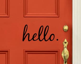 May include: A bright orange front door featuring four rectangular panels, a gold-toned metal door knocker, a matching gold handle, and the word hello written in black cursive script on the center right side of the door surface.