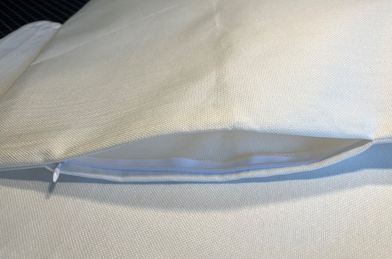 May include: A white pillow cover with a zipper closure. The cover is made of a soft, woven fabric.