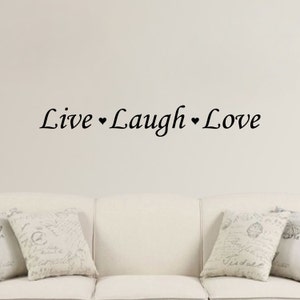 May include: A white wall with the text "Live ♥ Laugh ♥ Love" in black cursive lettering. A white couch with two pillows is in the foreground.