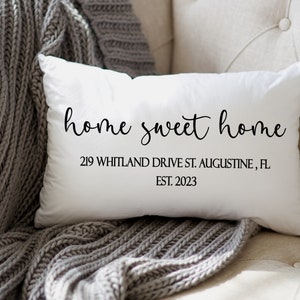 May include: White throw pillow with black text that reads "home sweet home" and "219 WHITLAND DRIVE ST. AUGUSTINE, FL EST. 2023".