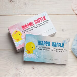 May include: A stack of pink and blue baby shower raffle tickets with a cartoon duck illustration. The text on the tickets reads "Diaper Raffle. Please bring a pack of diapers, any size, to be entered to win a great prize!"