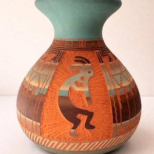 May include: A hand-painted ceramic vase with a turquoise rim and base. The orange body features a Kokopelli figure and geometric designs. The vase is approximately 10 inches tall, showcasing Southwestern artistry and craftsmanship.