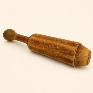 May include: A brown wooden pestle with a cylindrical body and a rounded handle. The wood features a weathered, textured surface with visible grain patterns and a distinct horizontal crack running along the side of the main body of the tool.