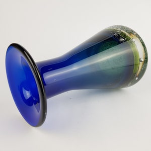 May include: A blue glass vase with a flared base and a green and white swirl design.