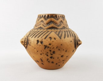 Może przedstawiać: Beżowy ceramiczny wazon o zaokrąglonym korpusie i wąskiej szyi. Wazon posiada ciemnobrązowe geometryczne wzory wokół szyi i korpusu, z małymi uchwytami po bokach. Powierzchnia ma nakrapianą teksturę.
