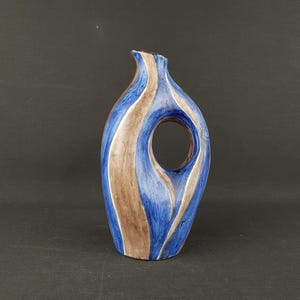 May include: A ceramic vase with a unique design. The vase features a blue and brown color scheme with a large circular opening. The vase has a slender, elongated shape and is suitable for decorative purposes.