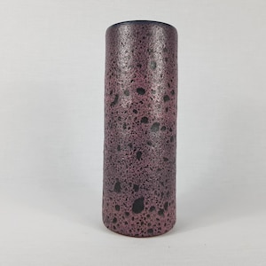 Könnte beinhalten: Eine zylindrische Keramikvase in rosa und schwarz mit Flecken.