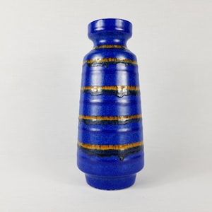 May include: A blue ceramic vase with brown and gold stripes. The vase has a wide mouth and a narrow base.
