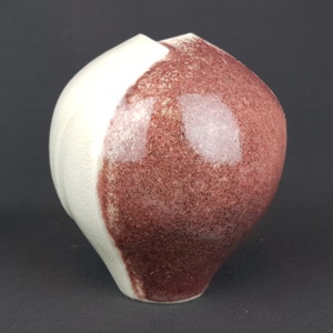 Könnte beinhalten: Eine Keramikvase mit weißer und burgunderfarbener Glasur. Die Vase hat die Form eines Herzens und eine glatte, glänzende Oberfläche.
