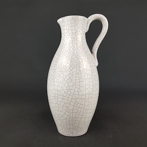 May include: White ceramic pitcher with a crackled glaze and a handle. The pitcher has a rounded body and a narrow neck.