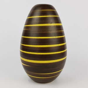 May include: An egg-shaped vase with a smooth, dark brown finish featuring horizontal, thin yellow stripes that wrap around the body. The vase has a narrow, rounded opening at the top and tapers toward a smaller, rounded base, creating a symmetrical form.