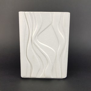 May include: White ceramic vase with a wavy, textured design.