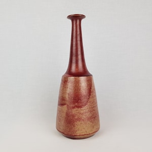 Puede incluir: Un jarrón de cerámica rojo y marrón con cuello estrecho y base ancha.