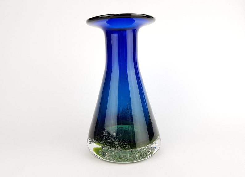 May include: A blue glass vase with a wide mouth and a green glass base. The vase has a clear glass rim and a textured green glass base.