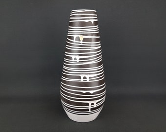 May include: A tall, white and brown ceramic vase with a striped pattern. The vase has a rounded bottom and a narrow opening.