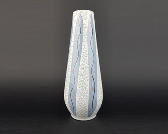 May include: A tall, white ceramic vase with a crackled glaze and blue and red geometric patterns.